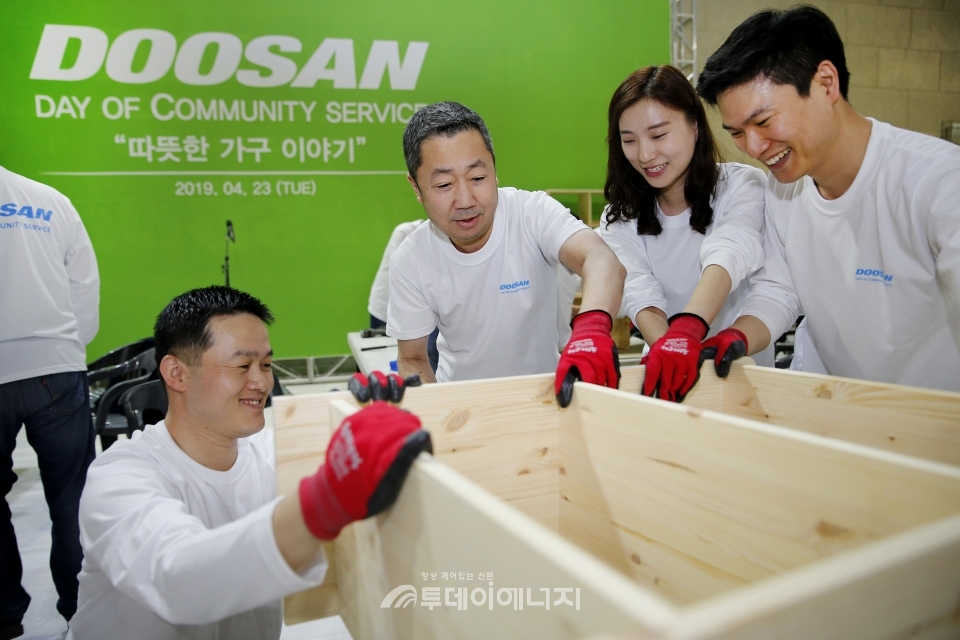 박정원 두산그룹 회장(가운데)이 임직원들과 함께 인근 지역 가정에 전달할 가구를 제작하고 있다.