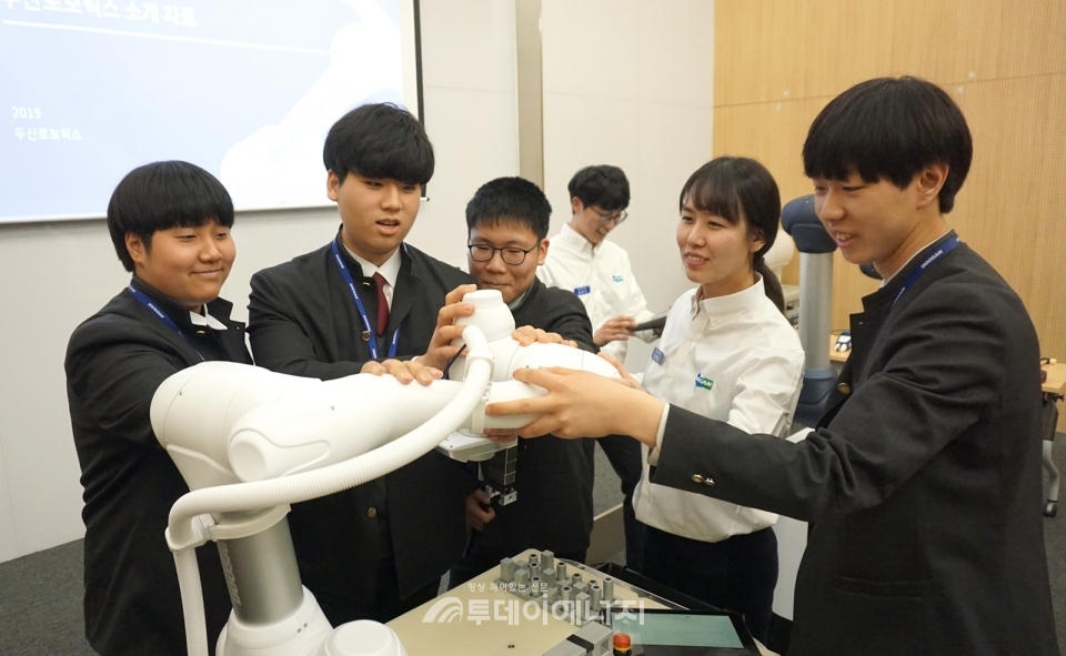 두산로보틱스 본사에서 열린 로봇 아카데미에 참가한 삼일공업고등학교 학생들이 두산로보틱스 연구원들과 함께 협동로봇을 시연하고 있다.