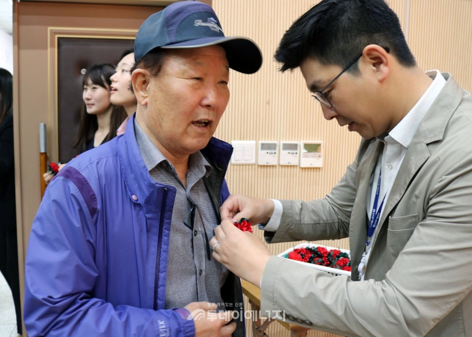 한국동서발전 직원이 어버이날 행사에 참여한 어르신께 카네이션을 달아드리고 있다.
