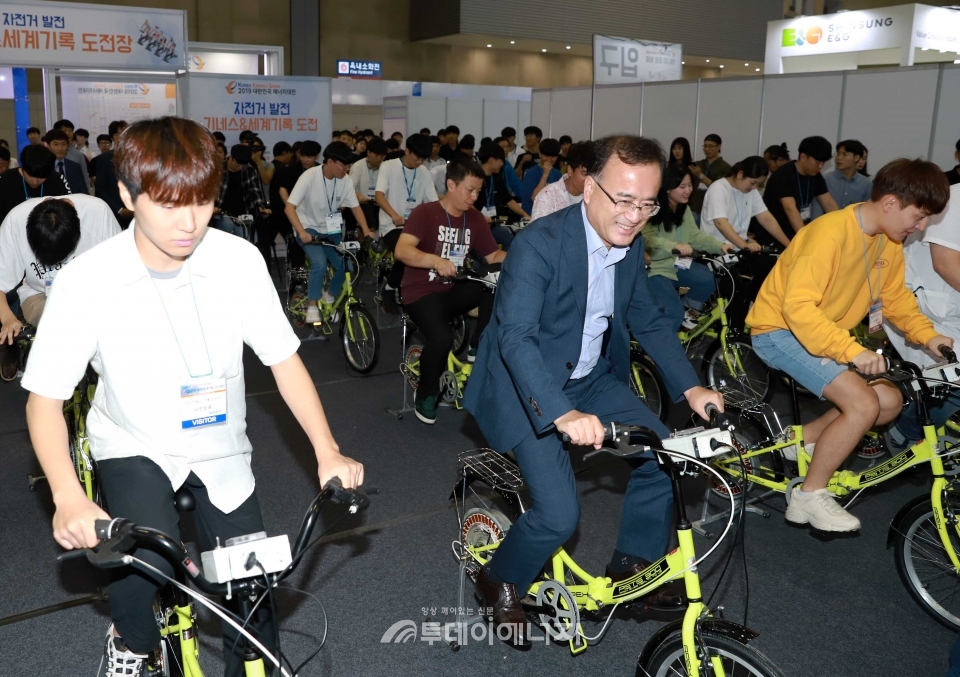 2019 대한민국 에너대전에서 진행된 ‘자전거 발전 기네스 및 세계기록도전’ 프로그램에서 이상홍 한국에너지공단 부이사장(가운데)이 자전거 발전기 패달을 밟으며 세계기록에 도전하고 있다.