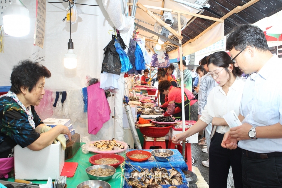 한국동서발전 직원들이 전통시장에서해산물 을 구매하고 있다.