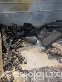 1톤 화물차 적재함에 불에 탄 나무토막과 부탄캔이 실려 있는 모습.
