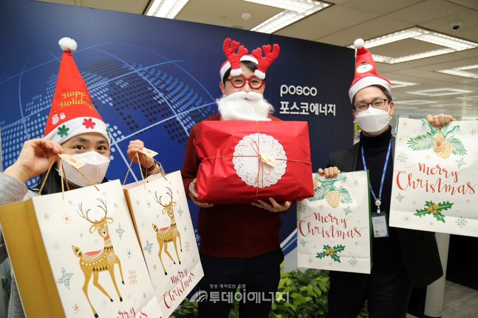 포스코에너지 직원들이 인천 서구 지역아동센터 어린이들에게 ‘맞춤형 크리스마스 선물’을 전달하기 전에 직접 포장한 선물 꾸러미를 들고 깜짝 산타로 변신해 환하게 웃고 있다.