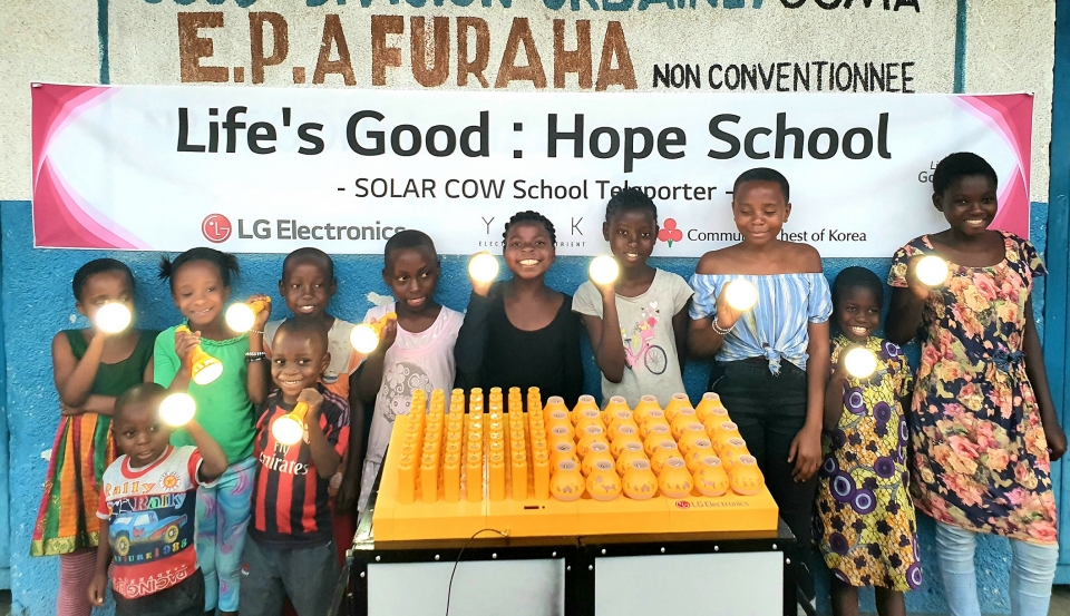 콩고민주공학국 프라하(Furaha) 초등학교 학생들이 LG전자가 설치한 친환경 태양광 충전시스템 ‘솔라카우’를 이용해 충전한 휴대용 보조 배터리를 사용하며 기뻐하고 있다.