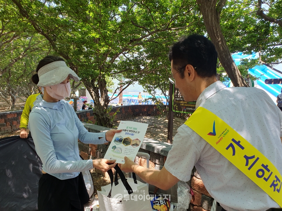 강도석 가스안전공사 인천본부 부장이 영흥도 십피포해수욕장 이용객에게 홍보용품과 부탄연소기 안전수칙 전단지를 나눠주고 있다.