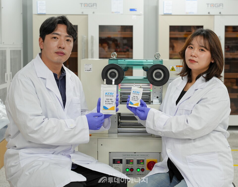 KERI 남기훈 박사(왼쪽) 및 김가람 연구원(UST 석사과정 졸업)이 중간층을 만드는 롤프레스 장비 앞에서 성과물을 선보이고 있다. / KERI 제공