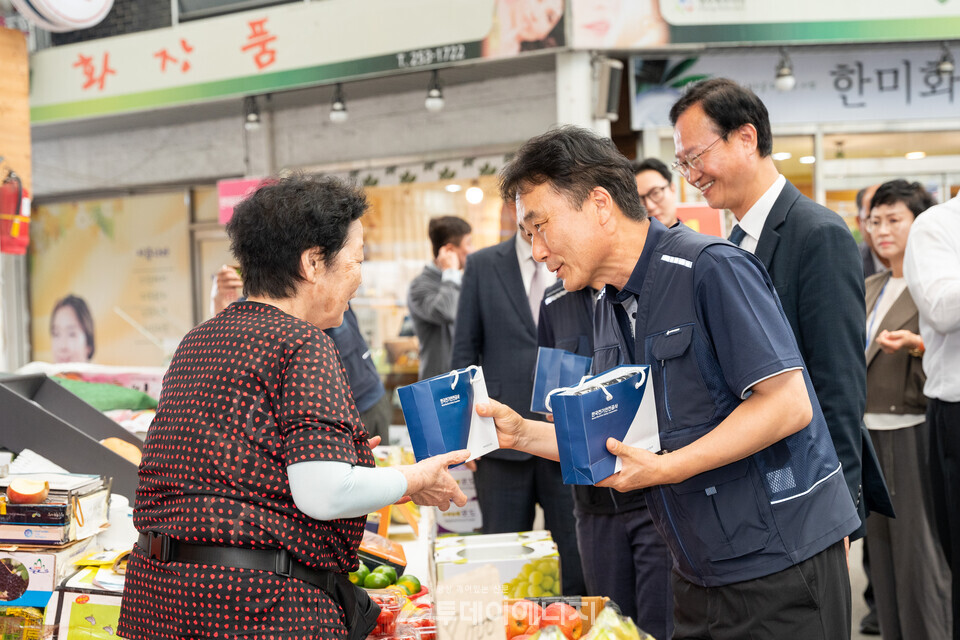한국전기안전공사 남화영 사장과 송재봉(뒷줄 오른쪽) 국회의원이 30일 충북 청주시 북부시장 상인들에게 기념품을 전달하고 있다. / 한국전기안전공사 제공