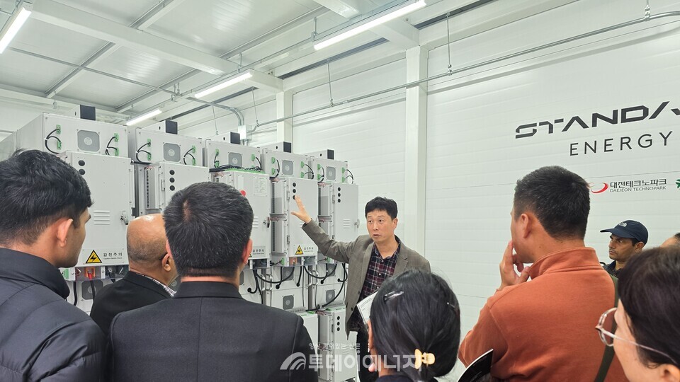 스탠다드에너지 김성진 상무(기술사업팀장)가 바나듐 이온 배터리 ESS 실증 현장에 방문한 부탄 에너지부 관계자 및 에너지 산업 관련 대표단에게 바나듐 이온 배터리 ESS에 대한 설명을 하고 있다.
